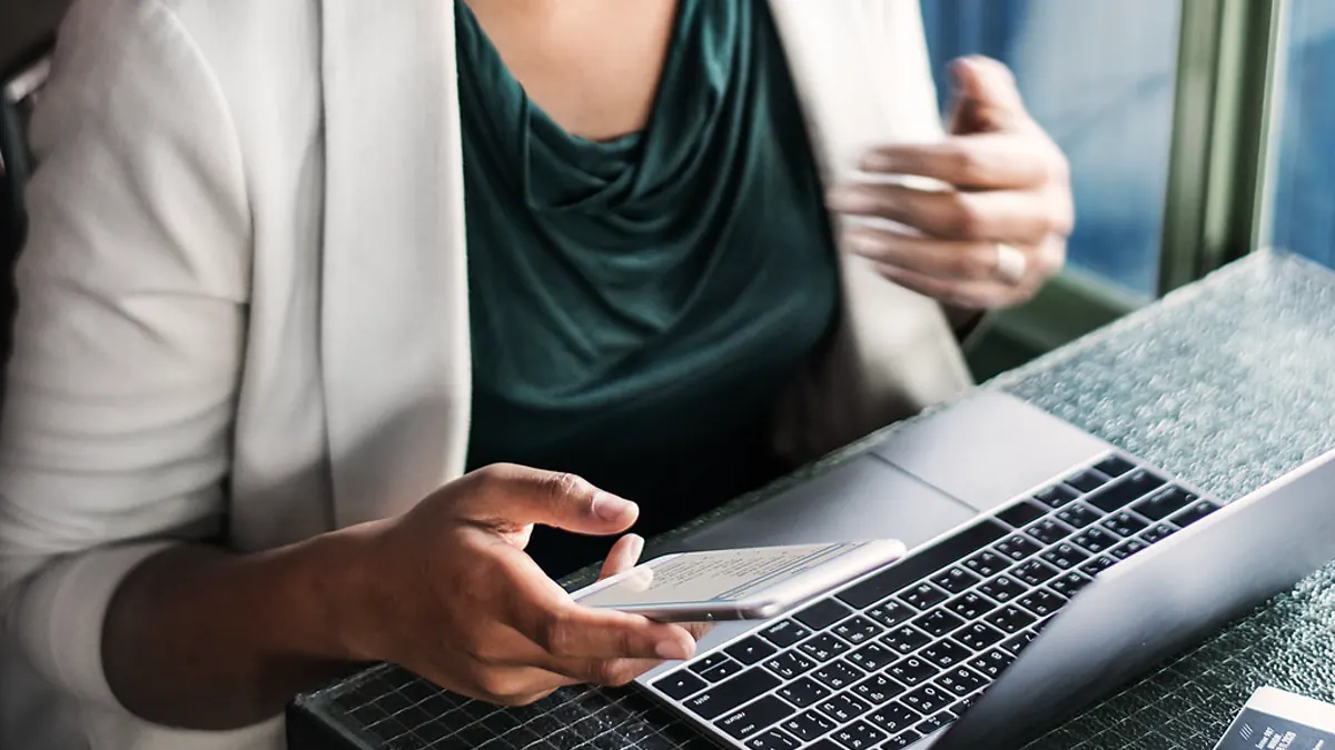 A person using a smartphone and laptop for public media research
